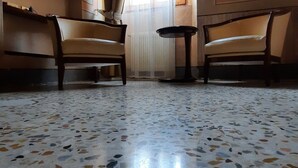 A room with two wooden chairs, a small round table, and a terrazzo floor. - Albergo Giulia Gonzaga (Sabbioneta)