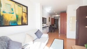 A modern living room with a white sofa, a glass coffee table, and a large abstract painting on the wall. - Armilla Apartament by A3Rentals (Armilla)