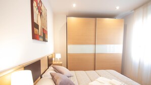A hotel room with a bed, bedside tables, a lamp, a painting on the wall, and a wardrobe. - Armilla Apartament by A3Rentals (Armilla)