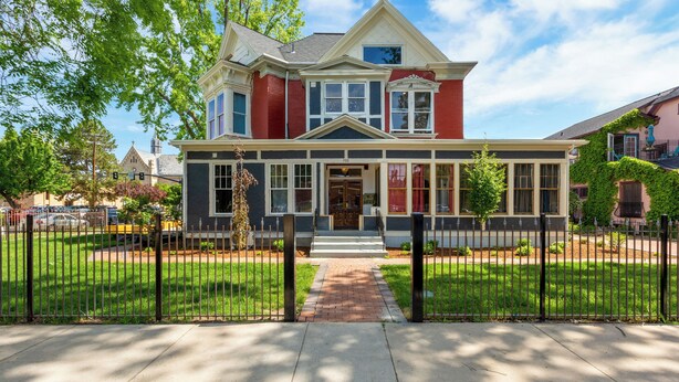 A two-story house with a front porch, a brick pathway leading to the entrance, and a black metal fence surrounding the property. - Boise-Historical-Northend-Downtown-Franklin 101 (Boise)