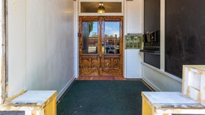 A hotel entrance with a wooden double door, a green carpet, and a blackboard on the wall. - Boise-Historical-Northend-Downtown-Franklin 101 (Boise)