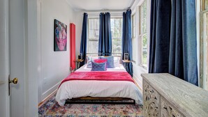 A bedroom with a large bed, a window with curtains, a painting on the wall, and a wooden bench. - Boise-Historical-Northend-Downtown-Franklin 101 (Boise)