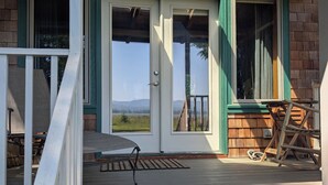A wooden house with a porch, a sliding glass door, and a view of the outdoors.