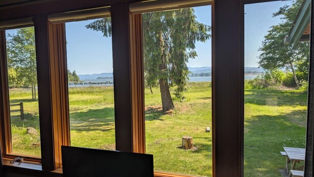 A room with large windows overlooking a grassy area with trees and a body of water.