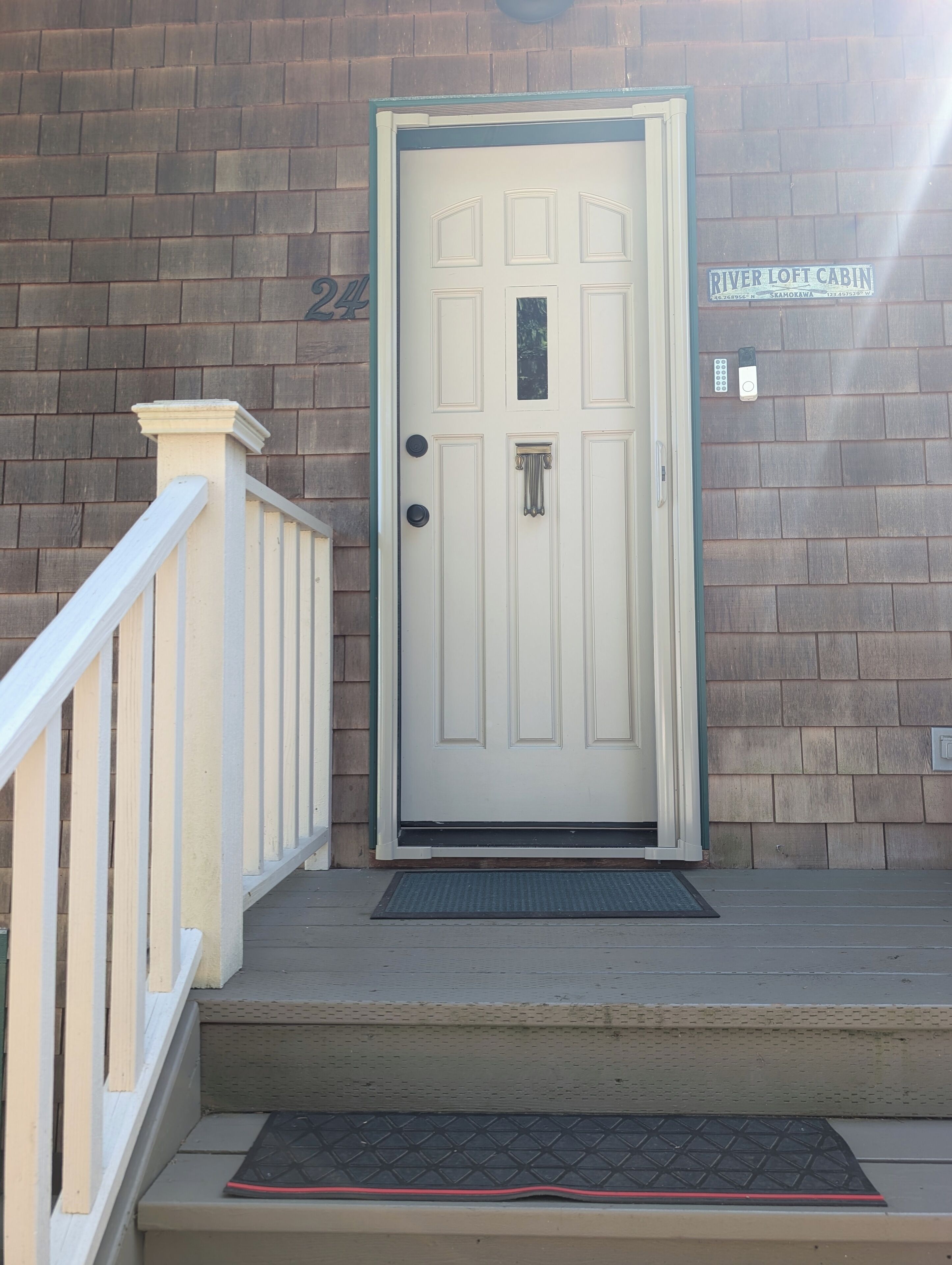 A white door with a small window, a mailbox, and a doorbell.