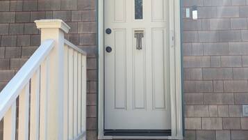 A white door with a small window, a mailbox, and a doorbell.