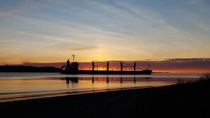 A cargo ship docked at a pier during sunset.