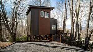 Una cabaña con fachada de madera, una terraza y una escalera que conduce a una ventana.