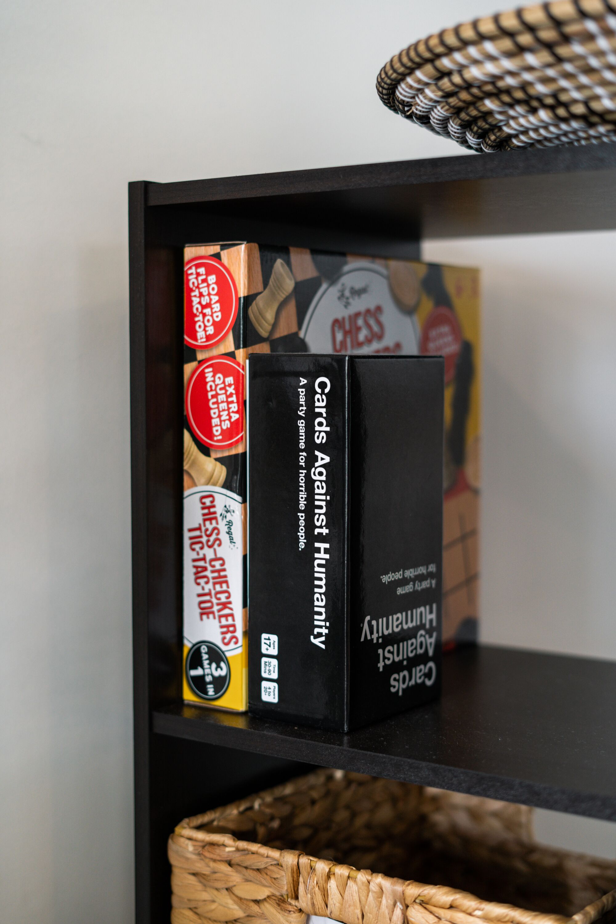 A shelf with board games including Chess and Cards Against Humanity.