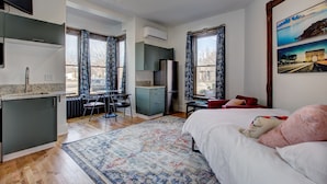 Una camera d'albergo moderna con angolo cottura, zona pranzo e un letto grande.
