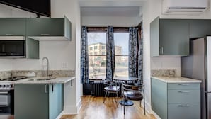 Cucina compatta con isola centrale, elettrodomestici integrati e vista all'esterno.