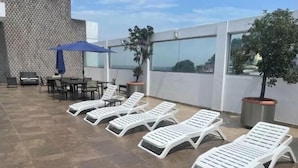 A rooftop terrace with sun loungers, a table with chairs, and potted plants. - Nice apartment, Las Penas-Riverfront 1 (Guayaquil)