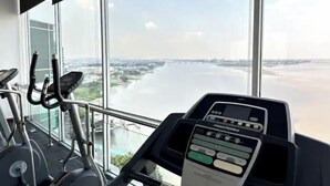 A gym with a treadmill and exercise equipment, large windows with a view of a river and cityscape. - Nice apartment, Las Penas-Riverfront 1 (Guayaquil)