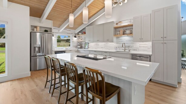 A modern kitchen with a large island, stainless steel appliances, and white cabinetry. - AC IN ALL 4 BEDROOMS! Recently renovated 4BD/3B Queen's Bath home w/Jacuzzi! (Princeville)