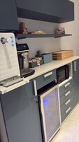 Una kitchenette con cafetera, microondas y cajones para guardar objetos.