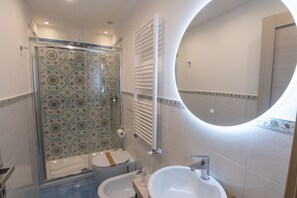 Ein Badezimmer mit Dusche, zwei Waschbecken, Toilette und Spiegel.