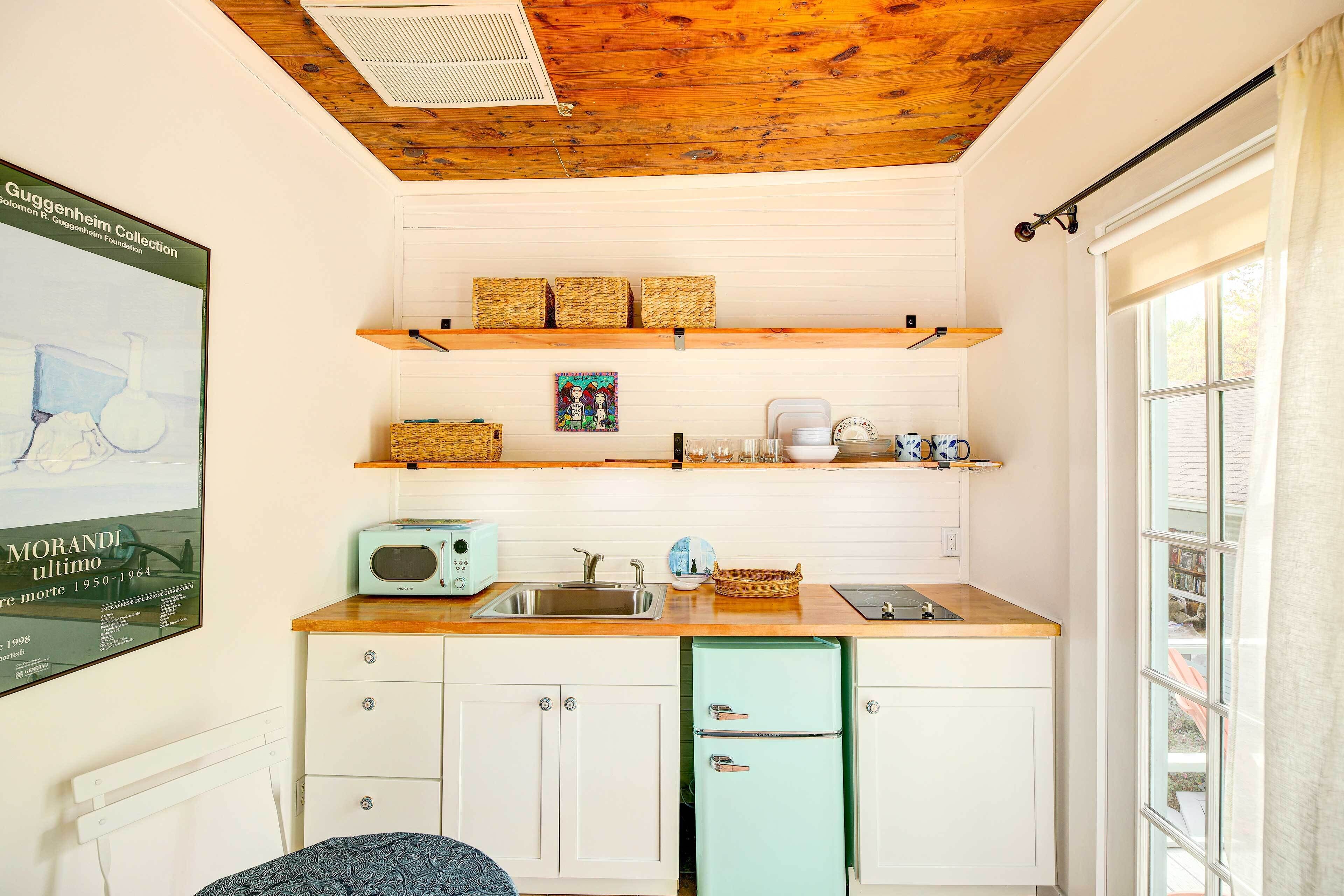 A compact kitchen with a wooden countertop, a vintage-style microwave, and a small refrigerator.