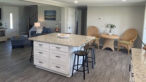 A spacious kitchen with a large island, wooden flooring, and modern bar stools. - The Yellowfin Inn- Down East Vacation Home with Sound Side Views (Gloucester)