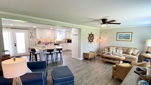 A spacious living area with a kitchen, a dining area, and a seating area with a sofa and ottoman. - The Yellowfin Inn- Down East Vacation Home with Sound Side Views (Gloucester)