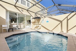 A swimming pool with a glass enclosure, a covered patio area, and a building with a beige exterior. - Featured- 3 Bedroom 3 Bath Private Pool! Windsor Hills Resort (Kissimmee)