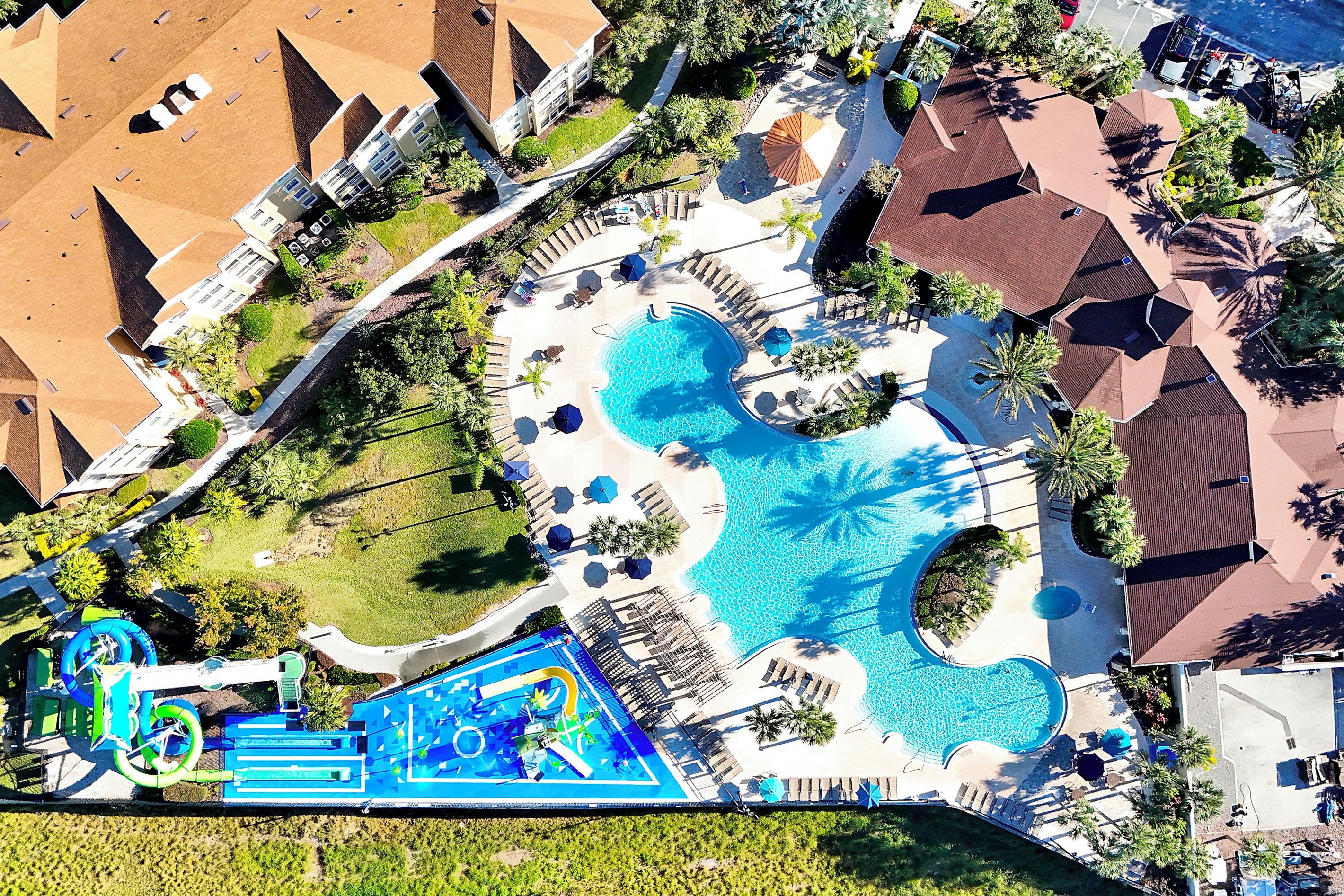 Oversigtsbillede af et resort med flere swimmingpools, liggestole og en vandrutsjebane.