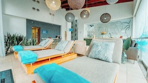 A modern spa room with a large bed, two lounge chairs, and a reception area. - Southern Sun Silverstar (Krugersdorp)