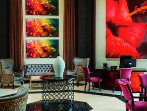 A hotel lobby with a sofa, chairs, a coffee table, and artwork on the walls. - Southern Sun Silverstar (Krugersdorp)