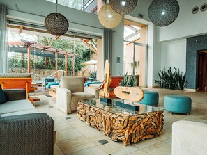 A spacious lobby with a glass coffee table, comfortable seating, and a guitar.
