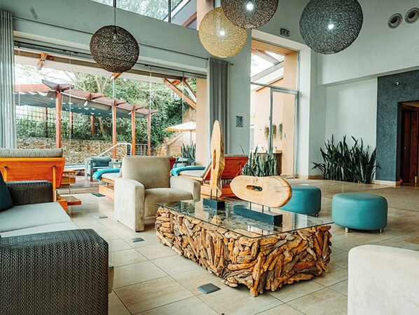 Un hall d’entrée spacieux avec une table basse en verre, des sièges confortables et une guitare.