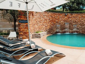 Zona de piscina con sillones de descanso y un letrero que dice 'GUESTS ONLY'.