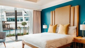Una habitación de hotel moderna con una cama grande, una mesita de noche, una silla y vistas al exterior.