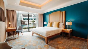 Une chambre d’hôtel moderne dotée d’un grand lit, d’un bureau, d’une chaise et offrant une vue sur l’espace extérieur abritant une piscine.