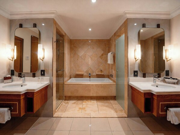 Un baño moderno con dos lavamanos, una bañera grande y una ducha con paredes de vidrio.