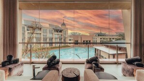 A modern hotel room with a large window overlooking a swimming pool and buildings. - Southern Sun Silverstar (Krugersdorp)