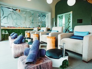 A modern spa room with multiple seating areas, including sofas and stools, and a large mirror wall. - Southern Sun Silverstar (Krugersdorp)