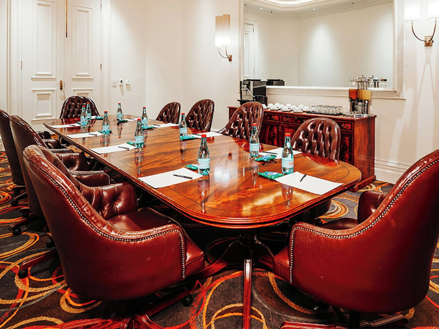 A conference room with a long table, leather chairs, and water bottles.