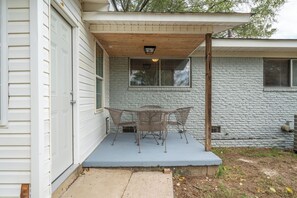 A covered patio with a table and chairs, a wooden ceiling, and a stone wall. - Fenced yard, downtown, pet friendly (Hot Springs)