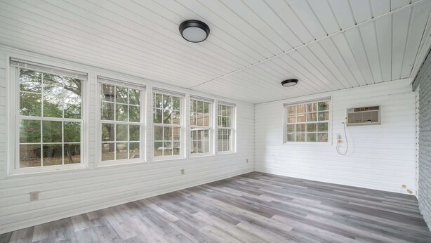 Una habitación con ventanas amplias, piso de madera y ventilador de techo.