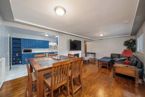 A spacious living area with a wooden dining table, a sofa, and a TV.