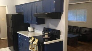 Una cocina compacta con armarios azul oscuro, un refrigerador negro y una estufa.