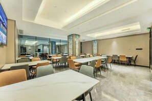 A modern hotel dining area with long tables and chairs, a large mirror, and a clean, well-lit space. - Elegant Stay Hotel (Shantou Jinhul Road Store) (Shantou)