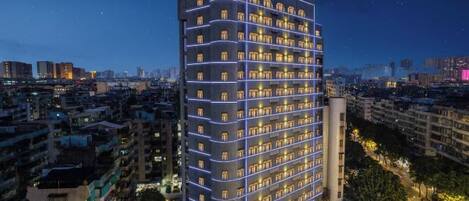 Un hotel de gran altura con varios pisos, un letrero llamativo en la parte superior y vistas del paisaje urbano circundante.