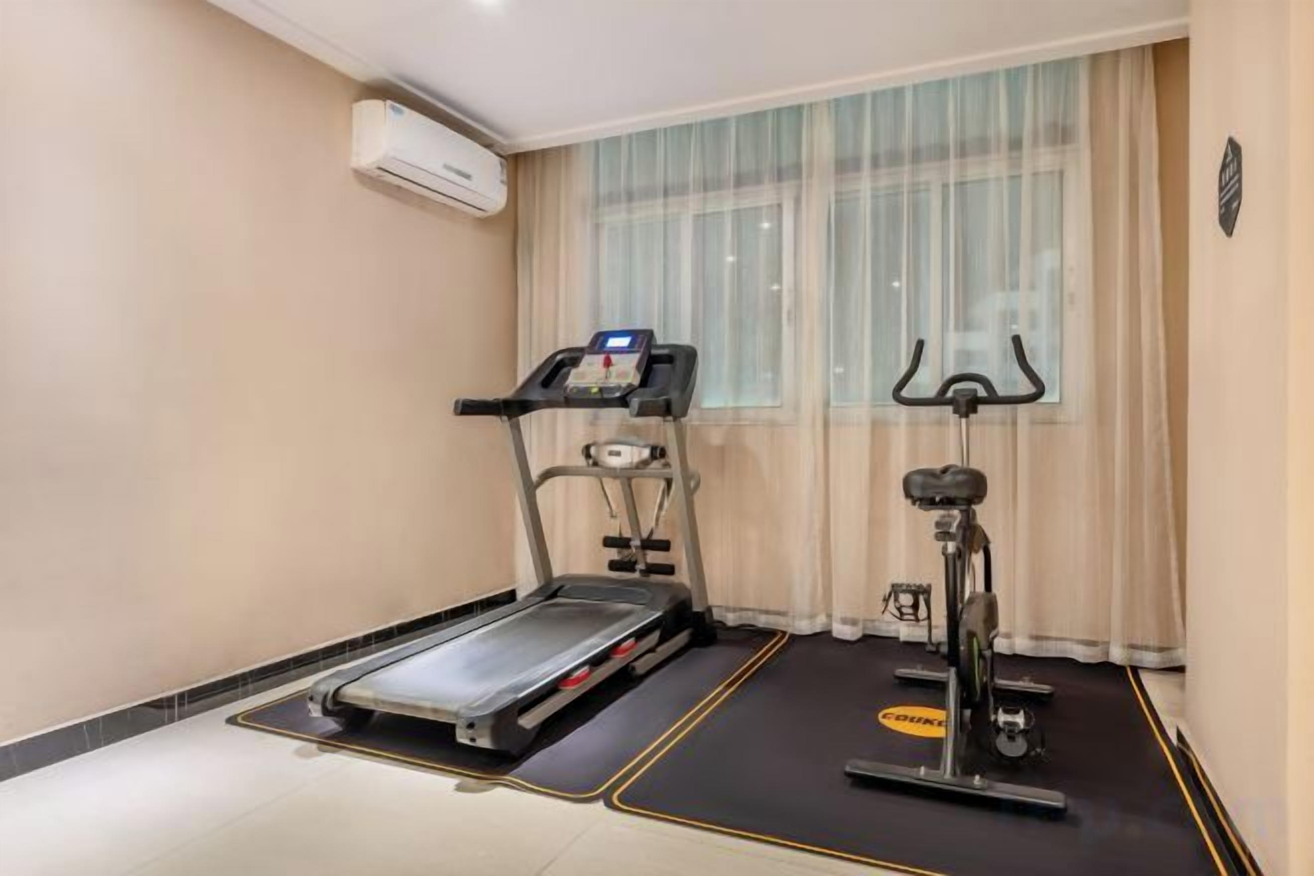 A room with a treadmill, a stationary bike, and a yoga mat.