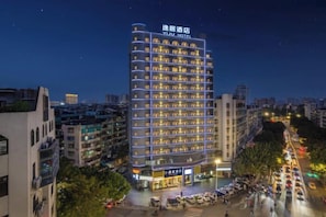 A multi-story hotel with a prominent sign at the top, surrounded by other buildings and a busy street below. - Elegant Stay Hotel (Shantou Jinhul Road Store) (Shantou)