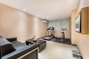 A modern living room with a sofa, a coffee table, and a treadmill in the background. - Elegant Stay Hotel (Shantou Jinhul Road Store) (Shantou)