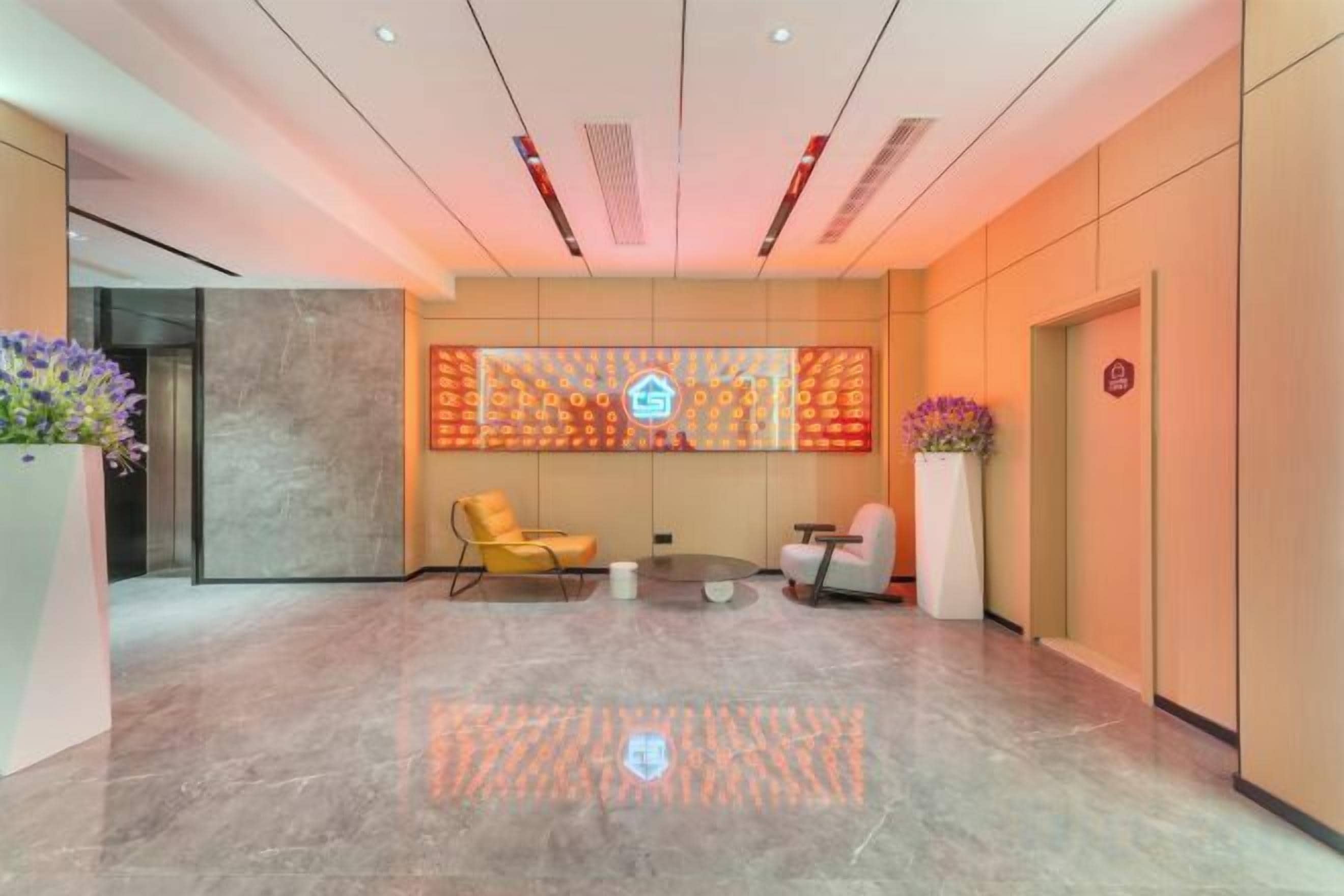 A lobby with a reception desk, seating area, and a decorative wall.