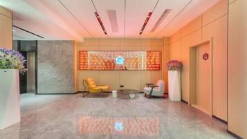 A lobby with a reception desk, seating area, and a decorative wall.