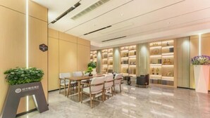 En moderne hotellobby med et marmorgulv, en reception, et siddeområde med stole og en vægdekoration med dekorative genstande.