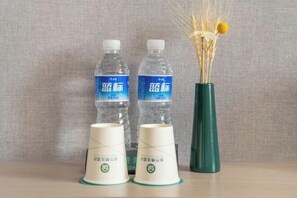 Zwei Wasserflaschen, zwei Pappbecher und eine Vase mit getrockneten Blumen auf einem Tisch.
