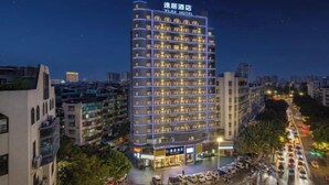 Et hotel med flere etager, oplyste vinduer og et skilt med teksten "YUU HOTEL".